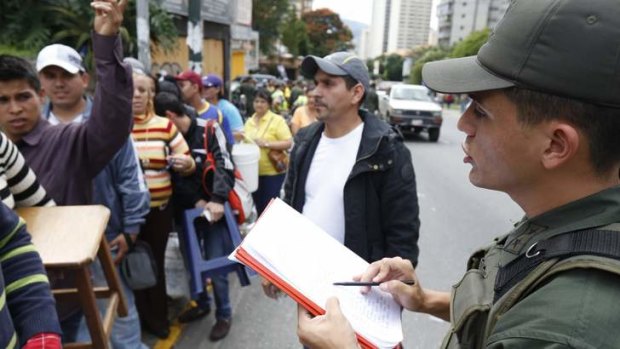 A Venezuelan soldier controls a crowd of people eager to buy electronic goods.  The government has sent soldiers to "occupy" a chain of electronics stores to stop price-gouging.