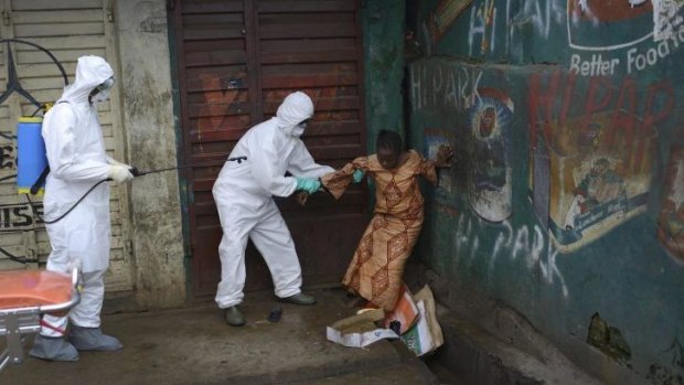 A woman suspected of being infected with Ebola is assisted by health workers to an ambulance for treatment in Freetown, Sierra Leone.
