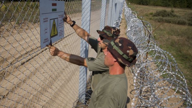 Soldiers from Hungary, which is in the Schengen zone, put up a sign warning in six languages that property damage is a criminal offence on a fence on the border with Serbia, which is not in the zone. 