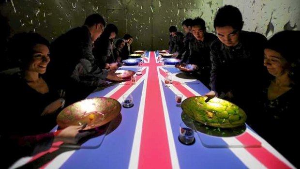 Guests are served dinner as a British flag is projected over the table of Ultraviolet restaurant in Shanghai.