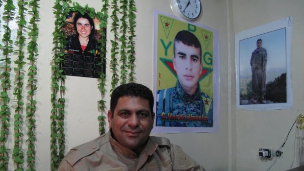 Hamid Derik, who is training new conscripts to Rojava's army, sits under a picture of 22-year-old Arin Mirkan, who ran into a group of Islamic State soldiers and blew herself up.