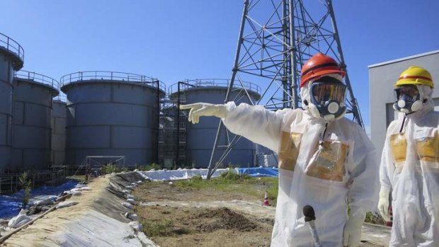 Japan's Economy, Trade and Industry Minister Toshimitsu Motegi (left), wearing a protective suit and a mask, inspects contaminated water tanks at the Fukushima Daiichi nuclear power plant.