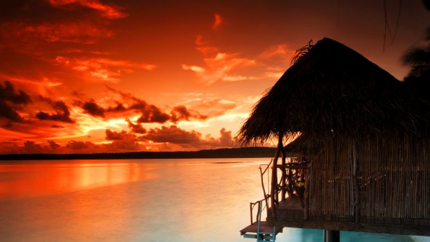 The sun sets over daytime bungalows at Aitutaki Lagoon Resort & Spa.