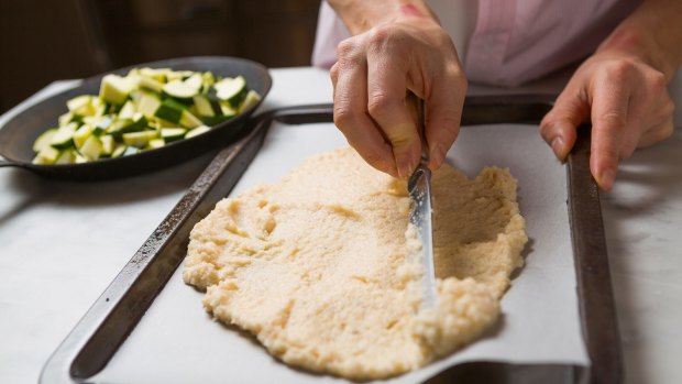 Preparing a pizza with a cauliflower base. 