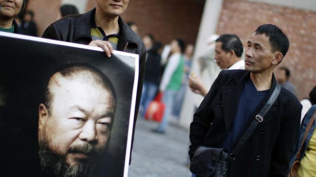A supporter of Ai Weiwei holds a picture of him at Weiwei's art studio to protest the demolition of the place by the government in Shanghai last November.