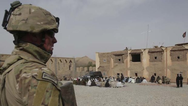 On guard ... Australian troops monitor a security shura, Afghanistan. The soldier's insignia has been digitally altered to protect his identity.