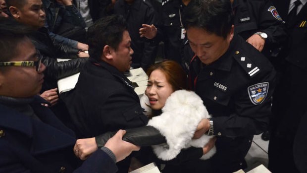 A woman is helped by police and airline personnel after being pushed by the crowd of stranded travellers.