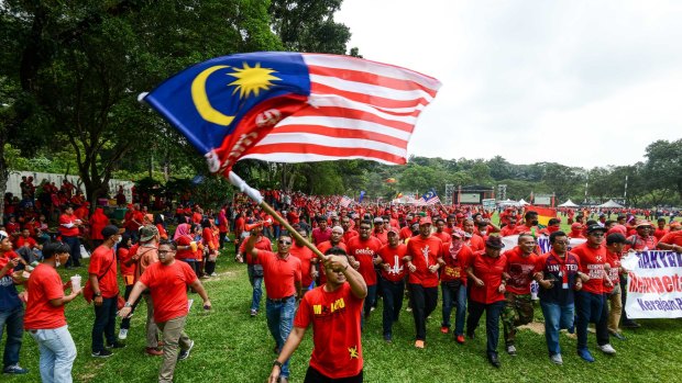 The protesters march behind the Malaysian flag. Their emphasis on Malay rights has aroused concern in the multi-ethnic nation.