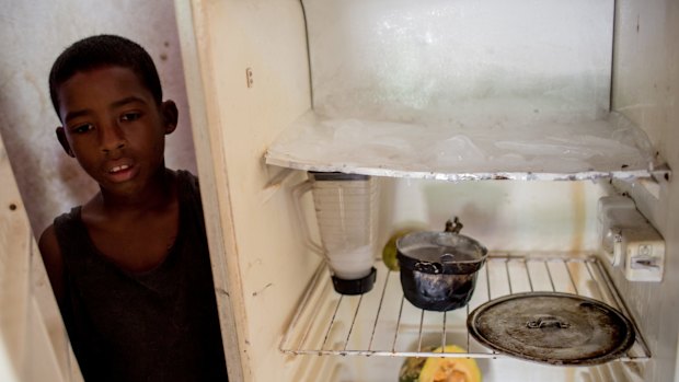 Joffren Polanco stands beside his almost empty fridge in Caracas.