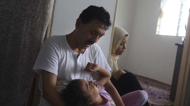 Afghan refugee Rajab plays with his eldest grandchild in the living room of their flat in Kuala Lumpur.