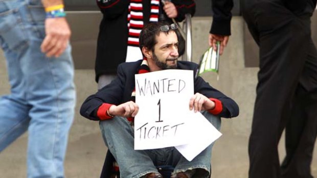 A lonely St Kilda fan sits out the front of the MCG hoping to be able to buy a ticket to the final.