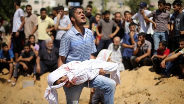 A Palestinian man at a funeral carries the body of a girl whom medics said was killed by an Israeli air strike.