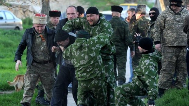 Pro-Russian militia set upon an unidentified man as Russian soldiers storm the Belbek airbase.