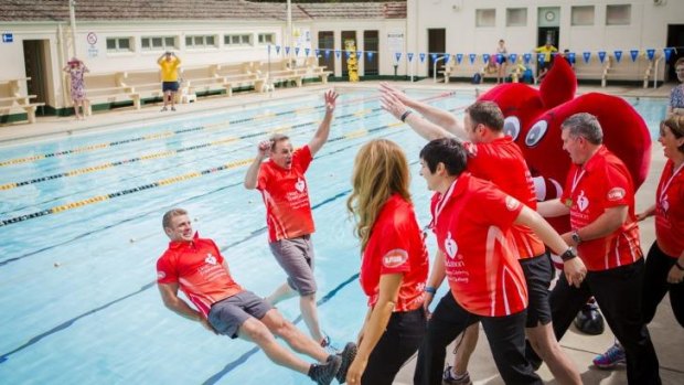 Top finish: Eleven Canberrans who took part in the Heart Foundation's 12-week Canberra Celebrity Heart challenge push personal trainer Lee Campbell and Heart Foundation ACT CEO Tony Stubbs into a pool to celebrate the end of the challenge.