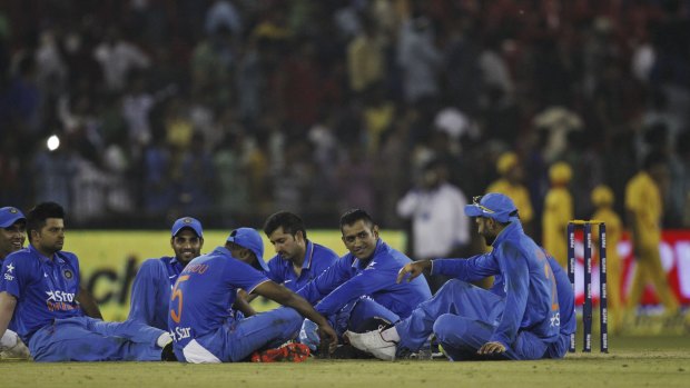 Disruption: Indian players sit in the ground during a halt in play due to poor crowd behaviour. 