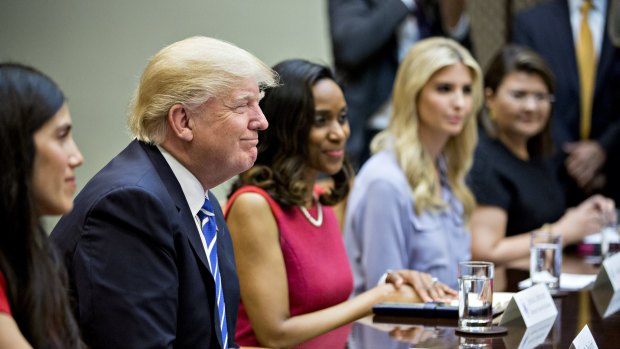 US President Donald Trump, left, smiles while meeting with women small business owners. 