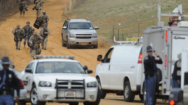 Heavily armed men move away from the home of Jimmy Lee Dykes in Midland City, Alabama during the siege in January.