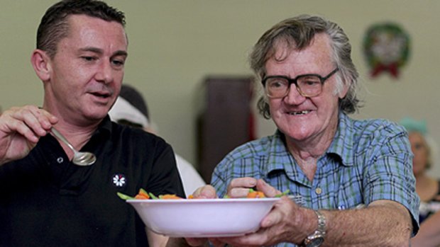 Michael Tudor from Micah Projects hands Robert Pearce some veges at the Christmas lunch.