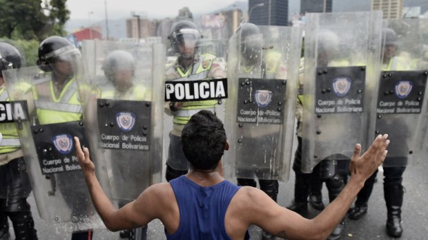 A protester gestures in front of police during an opposition march in Caracas on May 11.