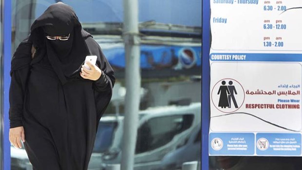 An Emirati woman passes by a dress code sign at a shopping mall in Dubai. An online campaign to get foreigns to dress respectfully has been gaining momentum.
