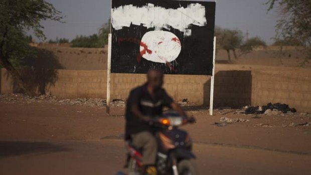 Sharia shunned ... a motorcyclist rides past a defaced sign for radical Islamist group MUJAO in Gao on Sunday.