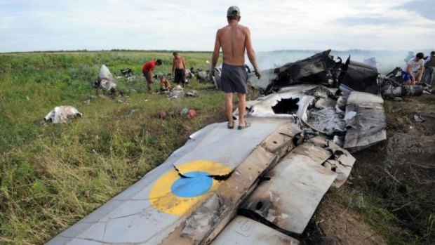 A man stands on the wreckage of a Ukrainian AN-26 military transport plane after it was shot down by a missile in the village of Davydo-Mykilske, east of Lugansk near the Russian border.