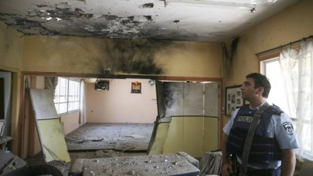 An Israeli policeman surveys a building damaged from a Palestinian mortar salvo.