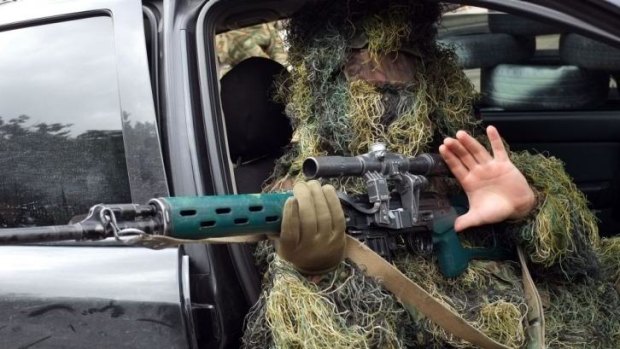 A pro-Russian sniper gestures as he sits in a car while guarding the front entrance of Lugansk's regional administration building.
