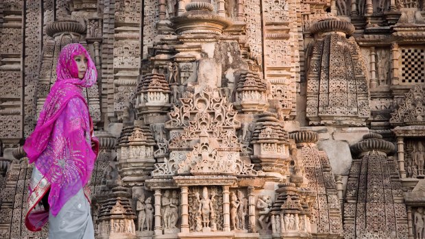 An Indian woman stands next to the carvings on the Khajuraho Temples in Madhya Pradesh, India. 