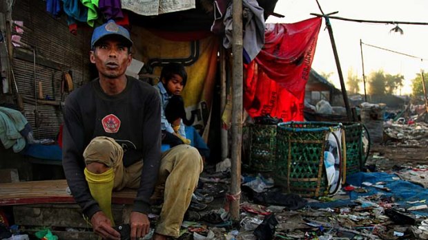 Sarwata and his daughter Nur Afdah, aged 10, get dressed in the early moring in one of the many makeshift villages surrounding the Bantar Gebang rubbish dump in the Bekasi district of Jakarta.