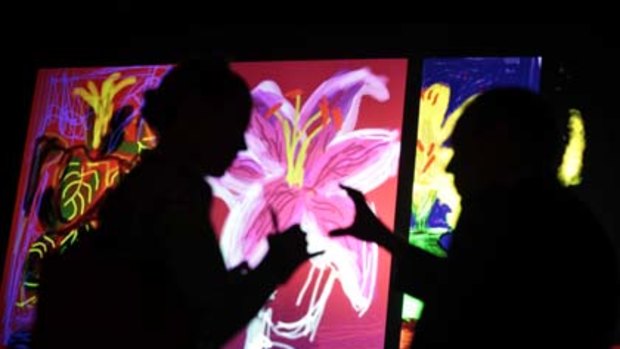 People chat in front of British artist David Hockney's artwork at the Pierre Berge foundation, in Paris.