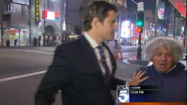 Steve Kuzj shoves the man out of shot in this screen grab from the KTLA 5 report.
