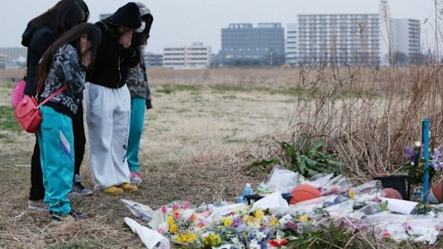 Friends pray for Ryota Uemura beside the Tama River in Kawasaki, near where the schoolboy's body was found in February. 