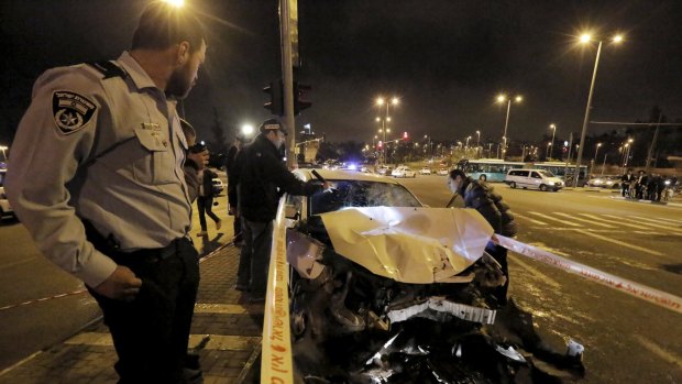 Israeli police officers examine the car used in a suspected attack in Jerusalem.