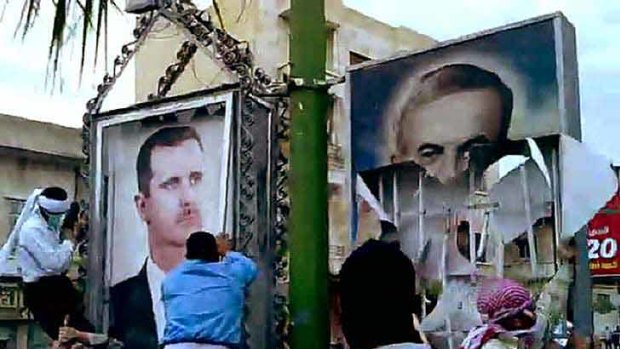 Protesters in Syria target posters of President Bashar al-Assad (left) and his late father, Hafez al-Assad.