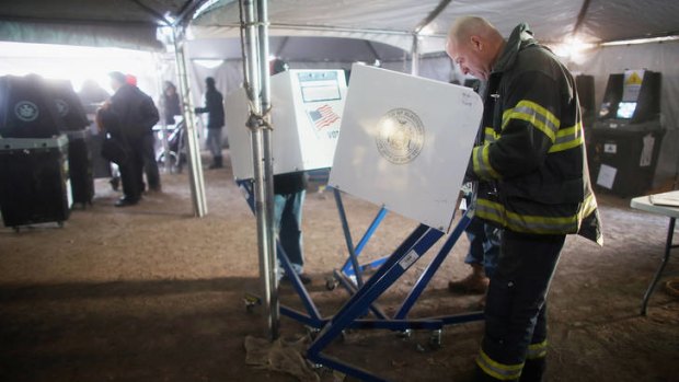 Vote goes on ... a Rockaway resident and New York City firefighter, Terence O'Donnell, marks his ballot in a makeshift tent set up as a polling place in the storm-hit Rockaways.