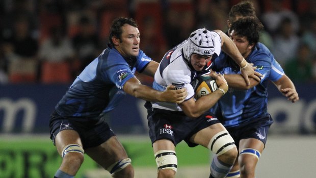 Pedrie Wannenburg of the Bulls, left goes for Ben Mowen of the Waratahs with Derick Kuun of the Bulls on the right during their Rugby Super14 match in Pretoria, South Africa.