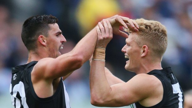 Winning feeling: Scott Pendlebury and Adam Treloar celebrate a goal in the Magpies' win over the Cats.

