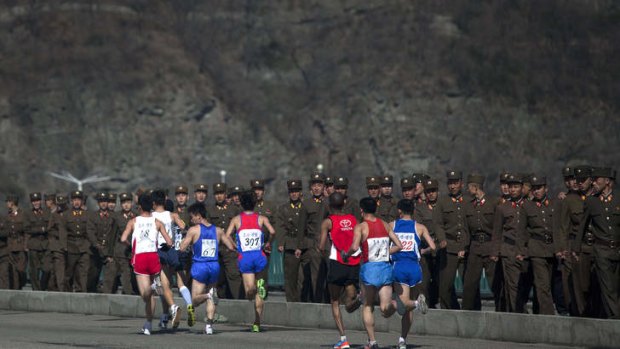 Running out of patience: North Korean soldiers watch marathon runners in the capital, Pyongyang, on Sunday.