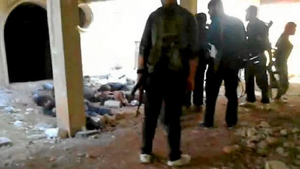 An image grab taken from a video uploaded on YouTube which purports to show rebel fighters gathered near the bodies of Syrian soldiers after they overran an army checkpoint in the northwestern Idlib province.