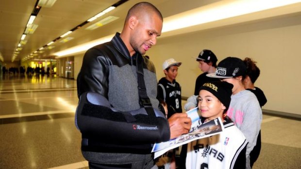 Patty Mills signs an autograph for Avari Petersen, 8, of Wright, at Canberra Airport.