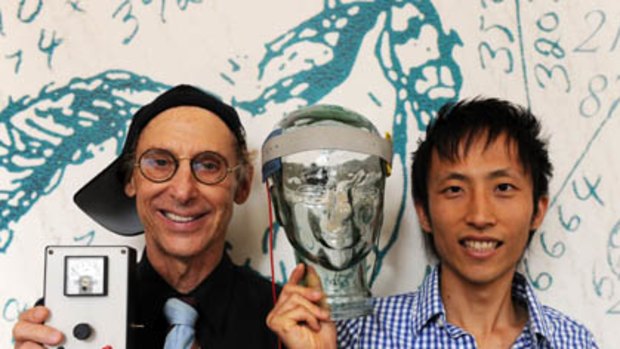 Professor Allan Snyder, left, and PhD student Richard Chi, right, display their "thinking cap" on a glass head at the University of Sydney.