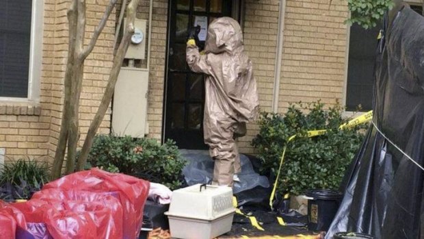 A man in a hazardous material suit prepares to remove a pet dog from the Dallas, Texas, home of a nurse infected with Ebola.