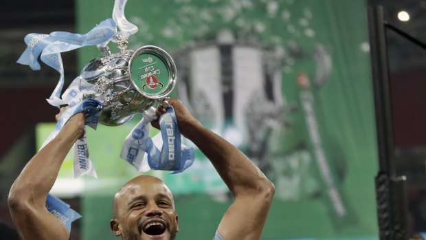 One down: Manchester City's Vincent Kompany with the first of what could be as many as four trophies for the English champions this season.