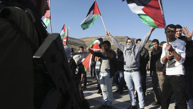 Tension ... protesters wave Palestinian flags in front of Israeli soldiers during a protest against Israel's military operation in Gaza.