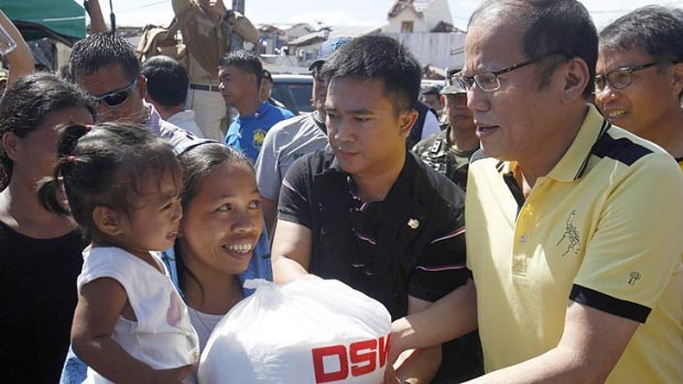 Crisis: Philippine President Benigno Aquino, right, distributes disaster relief items to survivors of Typhoon Haiyan during his visit to Palo.