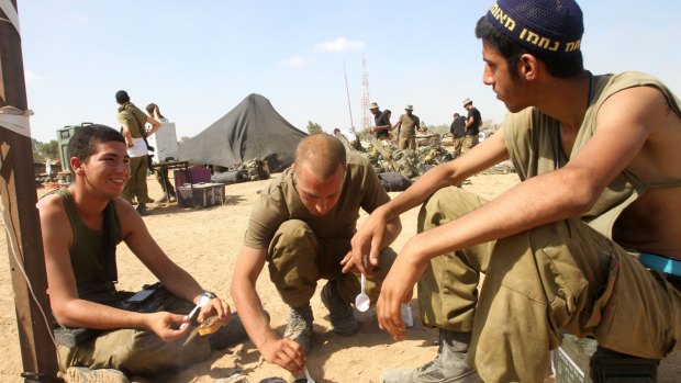Israeli soldiers from an infantry unit prepare food at an Israeli village on the border with Gaza on Sunday.
