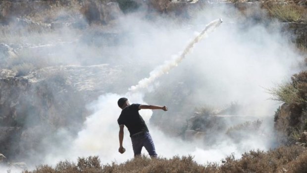 A Palestinian protester throws back a tear gas canister fired by Israeli soldiers during a demonstration near the West Bank city of Nablus.