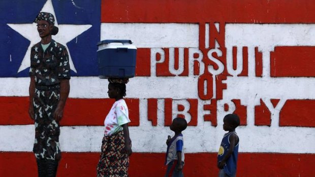 A local Liberian woman and children walk past a mural in Monrovia.