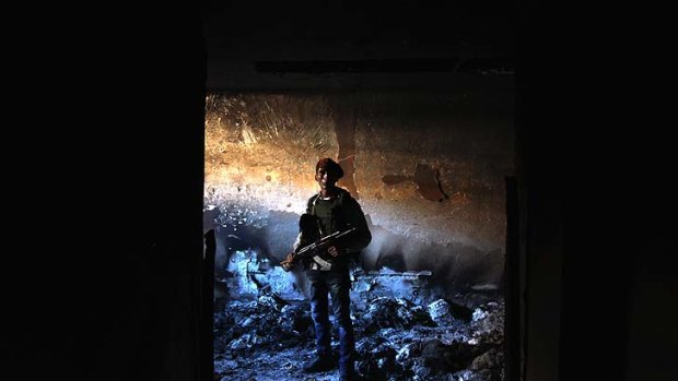 A rebel militiaman stands in the ashes of an alleged torture chamber of the former Libyan Internal Security force in Benghazi on Monday.